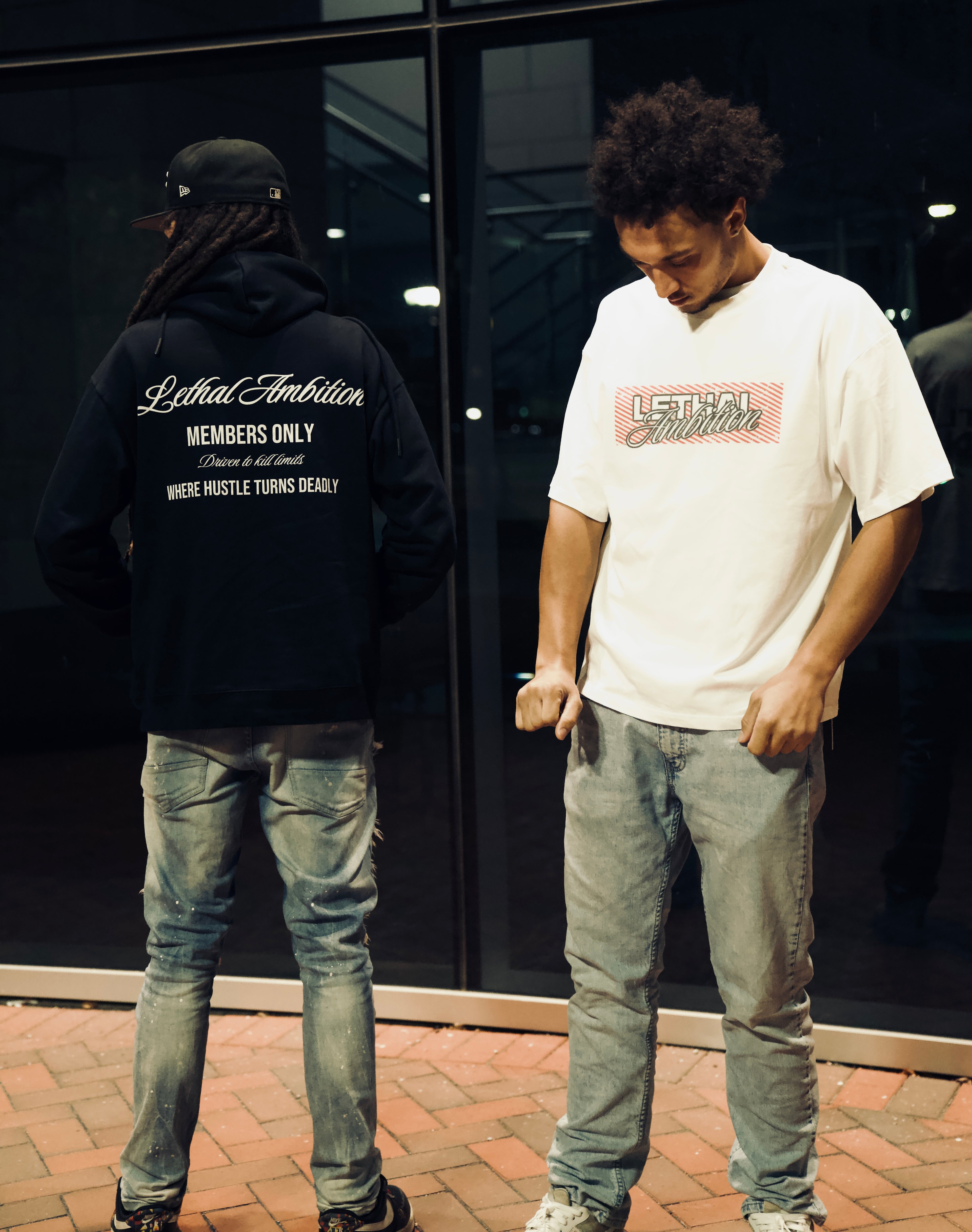 Two individuals wearing 'Lethal Ambition' branded clothing standing outside a building.